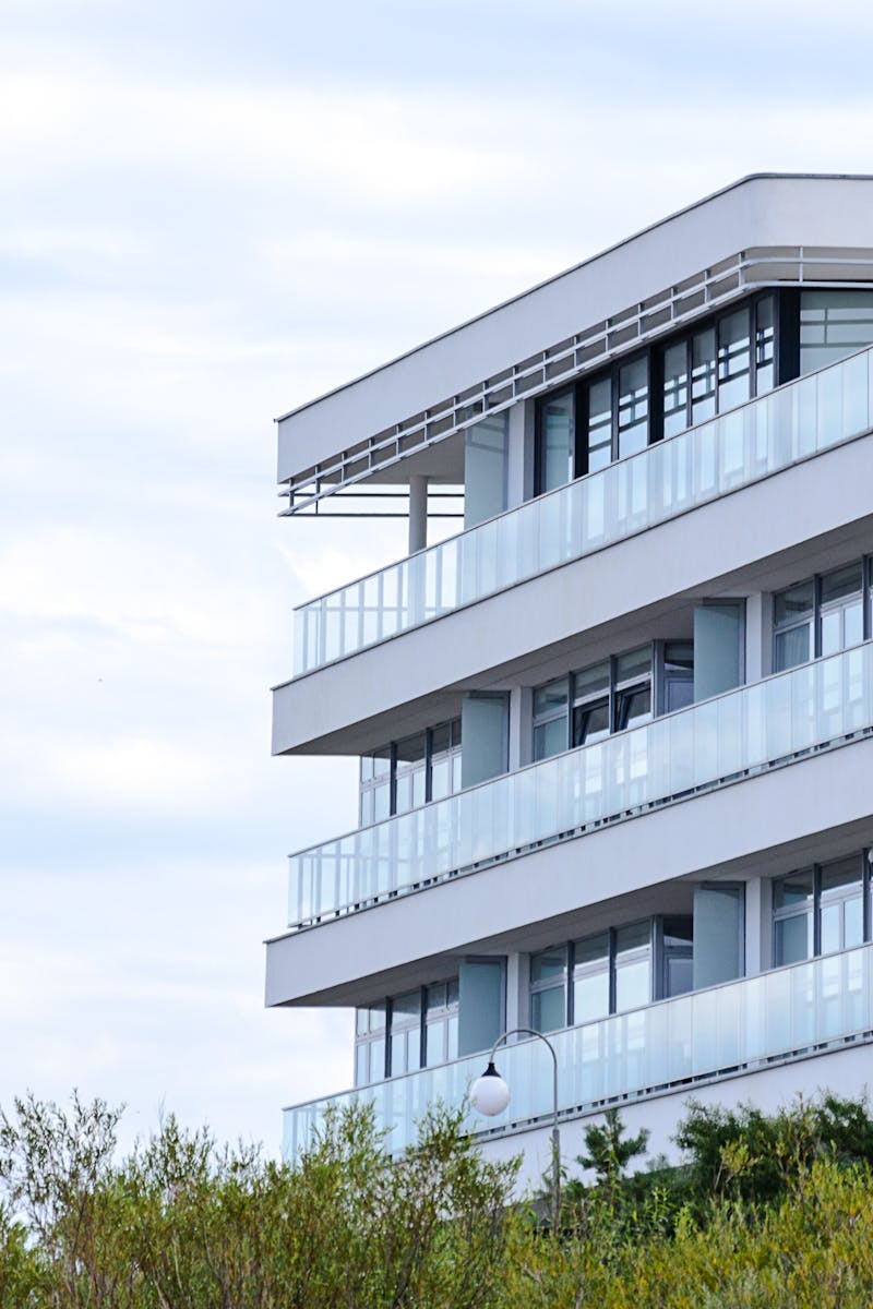 A contemporary apartment building with glass balconies and sleek design set against a clear sky.